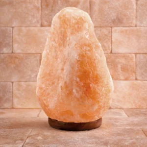 Naturalna lampa solna na drewnianej podstawce, zapalona, dająca ciepłe światło Naturalna lampa solna na drewnianej podstawce, zapalona, dająca ciepłe światło