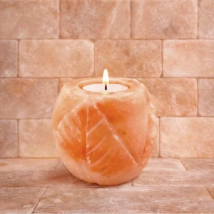 Rzeźbiony świecznik solny z różowej soli himalajskiej z zapaloną świeczką. Rzeźbiony świecznik solny z różowej soli himalajskiej z zapaloną świeczką.