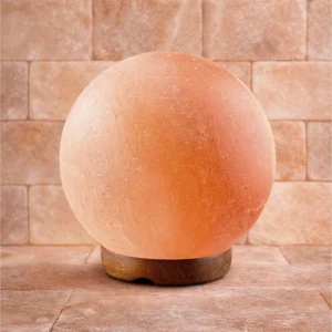 Zapalona rzeźbiona lampa solna w kształcie kuli na drewnianej podstawce Zapalona rzeźbiona lampa solna w kształcie kuli na drewnianej podstawce